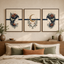 A three-piece framed wall art set hangs above a wooden headboard in a styled bedroom. The artwork features a central cream-toned print with a gold crescent moon and floral motifs, flanked by two matching prints showing a woman's profile with dark flowers and leaves.
